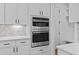 Modern kitchen appliances featuring stainless steel microwave and oven built into white cabinetry at 6120 Hutchins Dr, Buford, GA 30518