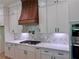 Modern kitchen features a pot filler over the gas range and custom cabinets with a wooden hood at 6120 Hutchins Dr, Buford, GA 30518