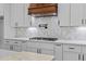 Close-up shot of kitchen with white cabinets, herringbone backsplash, and stainless steel gas cooktop at 6120 Hutchins Dr, Buford, GA 30518