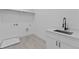 A bright and modern laundry room with a sink, white cabinets and a sleek black faucet at 6120 Hutchins Dr, Buford, GA 30518