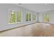 Sunlit living room boasts hardwood floors, large windows with scenic views, and a walkout balcony at 6120 Hutchins Dr, Buford, GA 30518