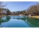 A tranquil pond reflects the surrounding trees and a house with an outbuilding under a clear blue sky at 96 Sam Alexander Rd, Douglasville, GA 30134