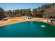 Aerial view of a pond with fountain, and surrounding wooded areas, near a home and barn at 96 Sam Alexander Rd, Douglasville, GA 30134