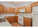 Bright kitchen features wood cabinets, white appliances, gas range, and hardwood flooring at 460 Tribble Gap Rd # 1004, Cumming, GA 30040