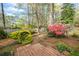 Lush backyard with stone features and mature azaleas and trees, and a wooden deck at 3595 Limberlost Sw Trl, Stockbridge, GA 30281