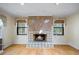 Inviting living room featuring a stone fireplace, hardwood floors, and large windows that allow plenty of natural light at 3595 Limberlost Sw Trl, Stockbridge, GA 30281