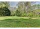 Spacious, green backyard featuring a well-maintained lawn, mature trees, and a quaint wooden fence at 4995 Hyde Ct, Cumming, GA 30040