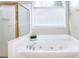 Bathroom featuring a tub with jets, a window with blinds, and a glass shower door at 2570 Middleton Way, Grayson, GA 30017