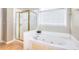 Bright bathroom featuring a large tub, gold shower door, and a window with blinds for privacy at 2570 Middleton Way, Grayson, GA 30017