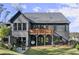 View of the home's backyard with a raised deck, lower patio, and large windows offering ample natural light at 4835 Fields Bridge Rd, Cumming, GA 30028
