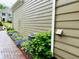 Exterior side view of a home with well-maintained siding, a brick pathway, and colorful flower beds at 9030 Brockham Way, Johns Creek, GA 30022