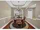 Inviting dining area beneath a tray ceiling, features a wooden table set upon a patterned rug at 241 Orchards Cir, Woodstock, GA 30188