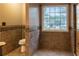 Tile bathroom with decorative tile accents, toilet, and a window that provides natural light at 703 Paul Revere Dr, Locust Grove, GA 30248