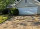 A two car garage with a concrete driveway and bushes lining the foundation at 3260 Rivermist Cv, Decatur, GA 30034