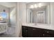 Bathroom with a dark vanity with white sink, mirror, and view into the bedroom with a window at 5705 Windjammer Pt, Cumming, GA 30041