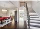 Bright entryway featuring hardwood floors, staircase, and view into dining room with modern chandelier at 5705 Windjammer Pt, Cumming, GA 30041