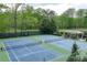 Two well-maintained tennis courts with a covered seating area, surrounded by lush greenery at 9044 Riverbend Manor, Alpharetta, GA 30022