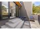 Inviting outdoor patio with sleek concrete steps, modern chairs, and a view into a kitchen through sliding glass doors at 10940 Serenbe Ln, Chattahoochee Hills, GA 30268