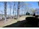 Spacious backyard featuring a mix of bare trees, green shrubbery, and black metal fence at 5712 Kendrick Ln, Cumming, GA 30041