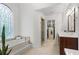 Bright bathroom boasts a soaking tub under a decorative window, leading to a walk-in shower and closet at 9985 High Falls Pointe, Johns Creek, GA 30022