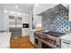 Chef's kitchen with Wolf range, stainless steel refrigerator, marble countertops, and custom tile backsplash at 9985 High Falls Pointe, Johns Creek, GA 30022