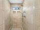 Modern shower featuring neutral tiling, recessed shelves, and dual shower heads, enhanced by a small window at 9985 High Falls Pointe, Johns Creek, GA 30022