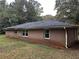 Side view of brick house with black roof, gutters, and a yard filled with fallen leaves at 2369 Christian Cir, Covington, GA 30016