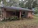 Rear exterior view of a brick house with a covered patio area and lush foliage at 2369 Christian Cir, Covington, GA 30016