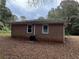 Back of brick home featuring an air conditioning unit and a yard covered in fallen leaves at 2369 Christian Cir, Covington, GA 30016