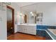 Well-lit bathroom features a tub with blue tile, a sink with storage, and wood floors at 3696 Suwanee Creek Ct, Suwanee, GA 30024