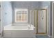 Bathroom featuring a shower, bathtub and large window with blinds at 1363 Brentwood Ln, Marietta, GA 30062