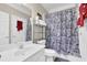 Bright bathroom featuring white vanity, toilet, and floral shower curtain, plus shelving for organized storage at 917 Redstone Trl, Dacula, GA 30019