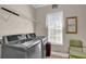 Well-lit laundry room with modern gray washer and dryer, convenient shelving, and a window for natural light at 917 Redstone Trl, Dacula, GA 30019