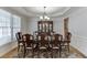 A formal dining room is brightly lit by a chandelier and natural light from a window at 1718 Autumn Sage Dr, Dacula, GA 30019
