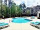 Community pool with lounge chairs surrounded by tall mature trees and residential buildings at 502 Clover Ln, Alpharetta, GA 30009