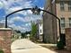 Stone archway and brick pillars mark the community entrance with sidewalks and manicured landscaping at 502 Clover Ln, Alpharetta, GA 30009