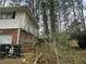 Exterior side view of home, showcasing a brick foundation, white siding, and lush natural surroundings at 3025 Mckenzie Rd, Atlanta, GA 30344