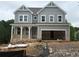 New home features gray siding, brick foundation, covered porch, and an attached two-car garage at 373 Riverwood Pass, Dallas, GA 30157