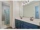 Well-lit bathroom featuring double sinks, a large mirror, blue cabinets, and a shower/tub combo at 45 Cherrystone Walk, Suwanee, GA 30024