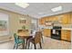 Eat-in kitchen features wood cabinets, black appliances, and a charming dining area with colorful chairs at 45 Cherrystone Walk, Suwanee, GA 30024