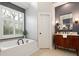 Elegant bathroom with soaking tub, shuttered window, and vanity with black hardware at 6935 York Pl, Cumming, GA 30040