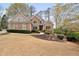 Charming brick home features a well-manicured lawn, mature trees, and beautiful landscaping at 6935 York Pl, Cumming, GA 30040