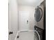 Laundry room with stacked washer and dryer, tiled floor and access to a white painted door at 6935 York Pl, Cumming, GA 30040