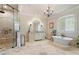 Spacious bathroom with travertine floors, glass shower, standalone tub, custom vanity, and chandelier at 931 Fairfield Dr, Marietta, GA 30068