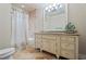 Bright bathroom featuring travertine tile, granite countertop, large vanity, and shower-tub with curtain at 931 Fairfield Dr, Marietta, GA 30068