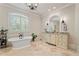 Bright bathroom features a standalone tub, travertine floors, custom vanity, and decorative chandelier at 931 Fairfield Dr, Marietta, GA 30068