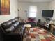 Comfortable living room features a leather sofa, a plaid rug, and a large flat screen television at 4691 Bo Hendrick Dr, Austell, GA 30106