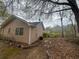 Back view of the house with tan siding, roof with antenna, and yard with leafy trees at 1430 Country Lane Ne Dr, Conyers, GA 30012