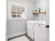 Bright laundry room with white washer and dryer, shelf and window providing natural light at 323 Fayetteville Rd, Decatur, GA 30030