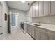 Well-organized laundry room featuring modern appliances, gray cabinetry, quartz countertops, and patterned tile flooring at 3669 High Green Dr, Marietta, GA 30068